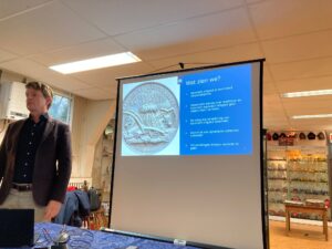 Een man staat voor een scherm met daarop een presentatie